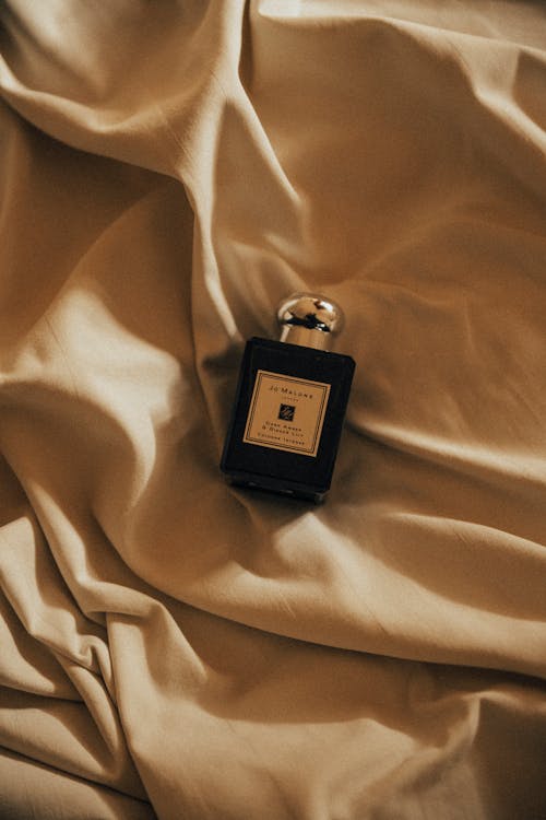 Close-Up Shot of a Black Perfume Bottle on a Brown Textile