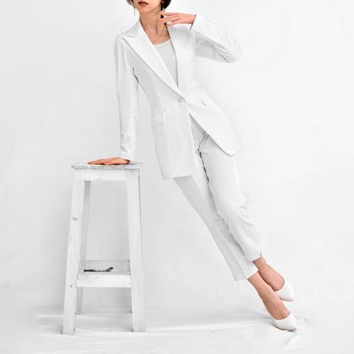 Free Elegant woman in all white outfit poses gracefully in a minimalist studio setting. Stock Photo