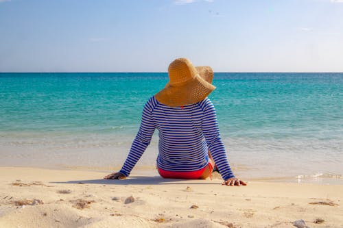 A Person Wearing Sun Hat Sitting on the Beach