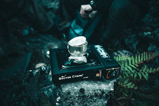 A portable gas stove heating a canned meal outdoors, perfect for camping.