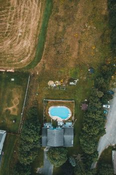 Stunning aerial shot of a house with a swimming pool amidst lush greenery, captured from above.
