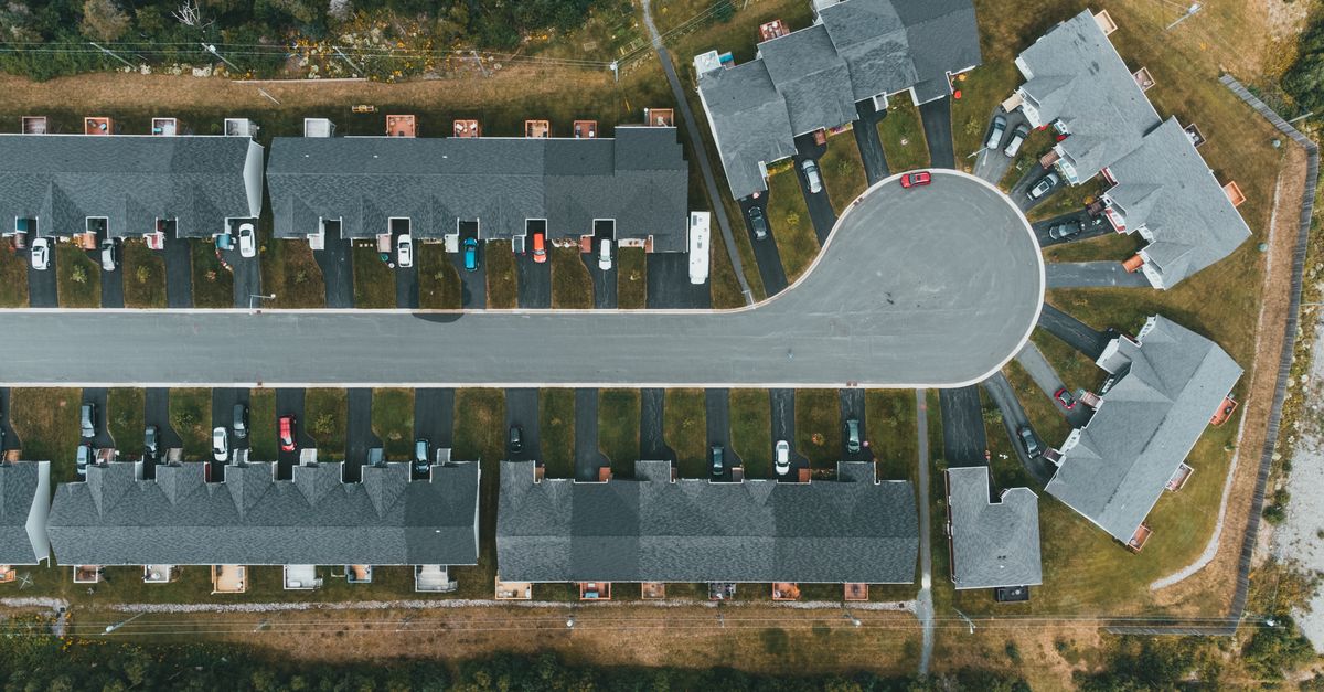 Drone shot of a modern suburban cul-de-sac featuring rows of townhouses and parked cars.