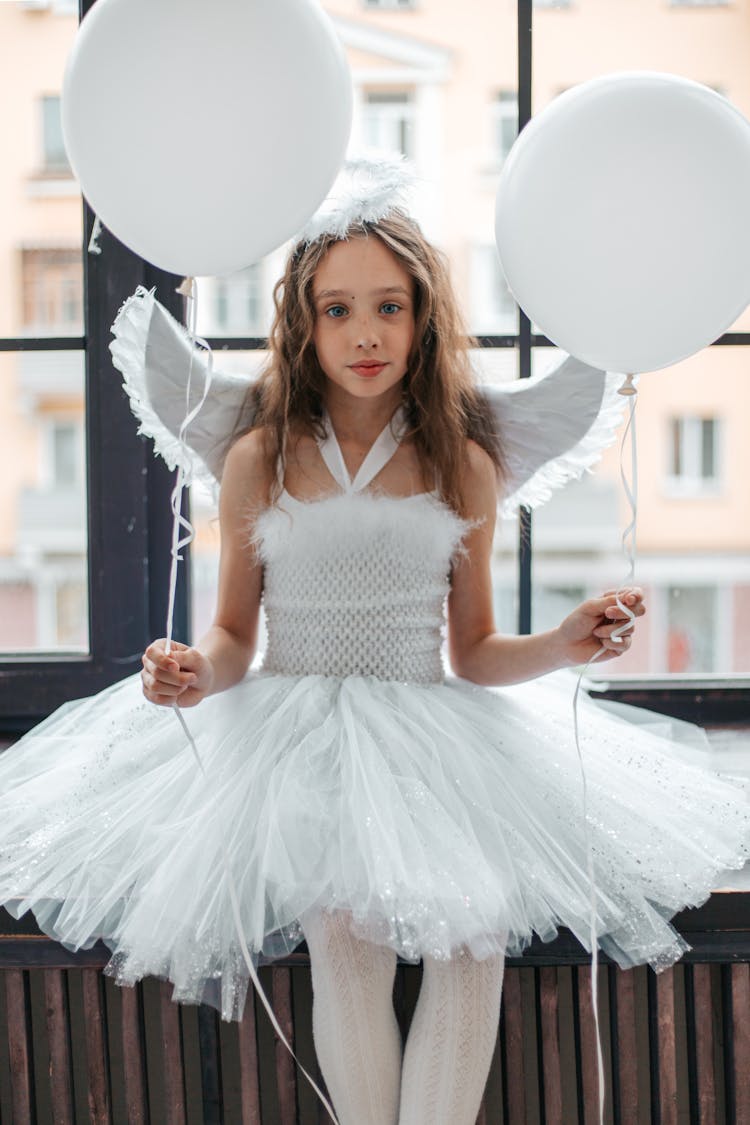 Young Brunette Girl Standing With Balloons In A Costume Of An Angel