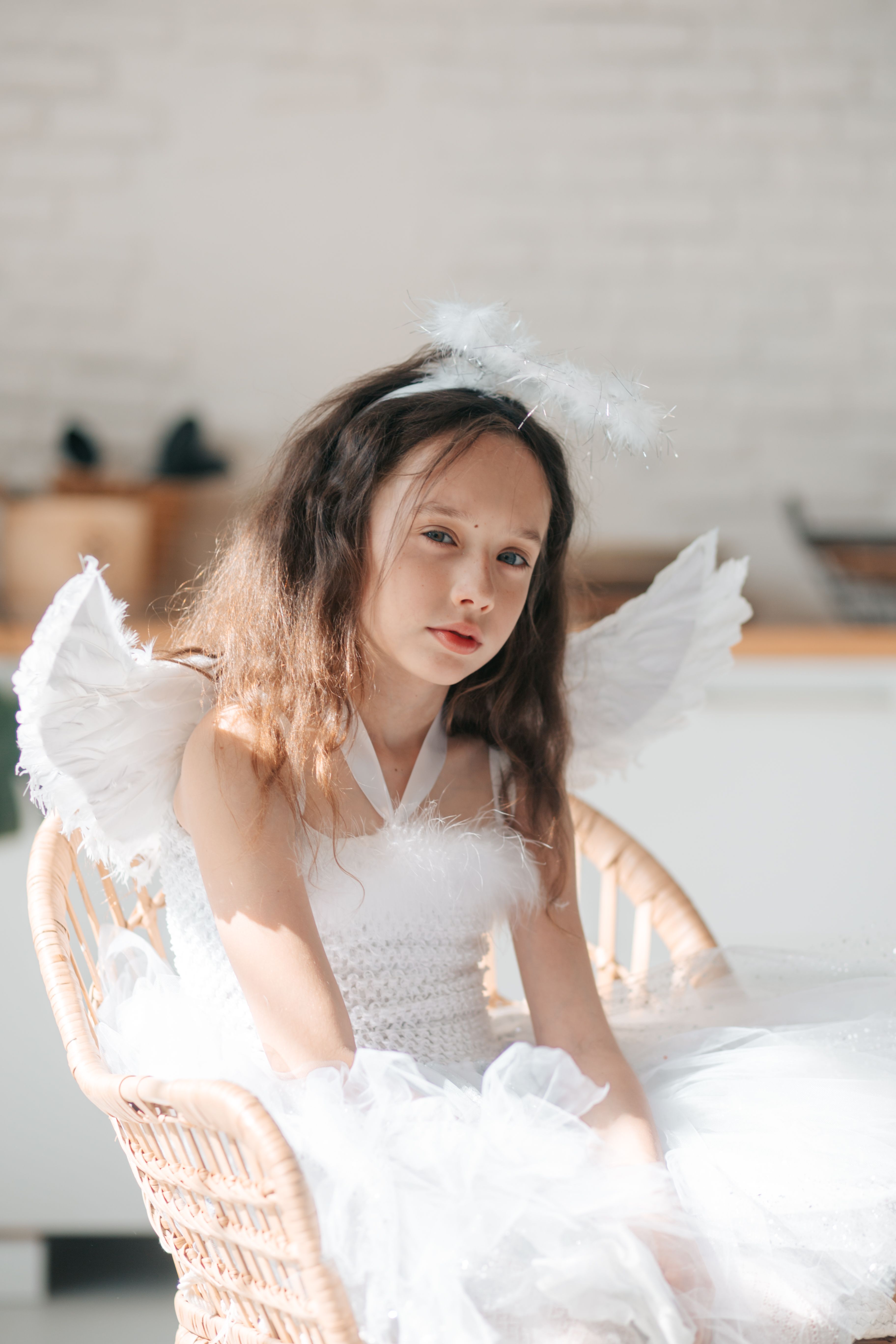 a pretty girl in angel costume sitting on a chair