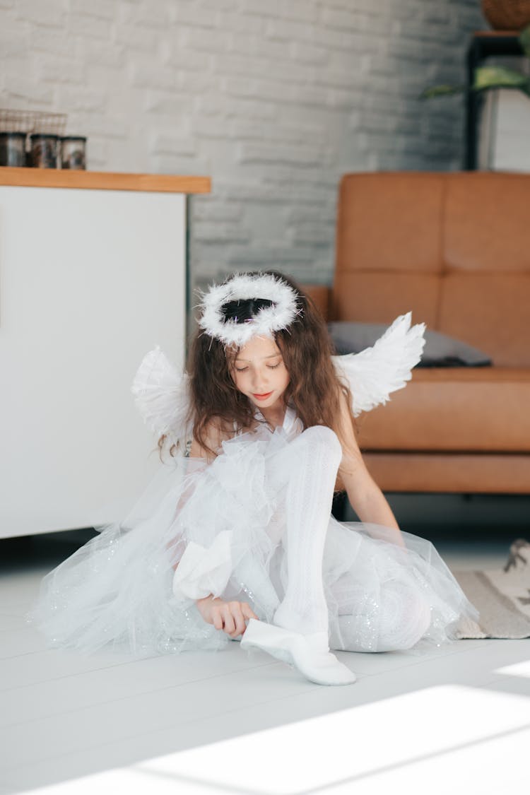 Cute Girl In Angel Costume Wearing Her White Shoe