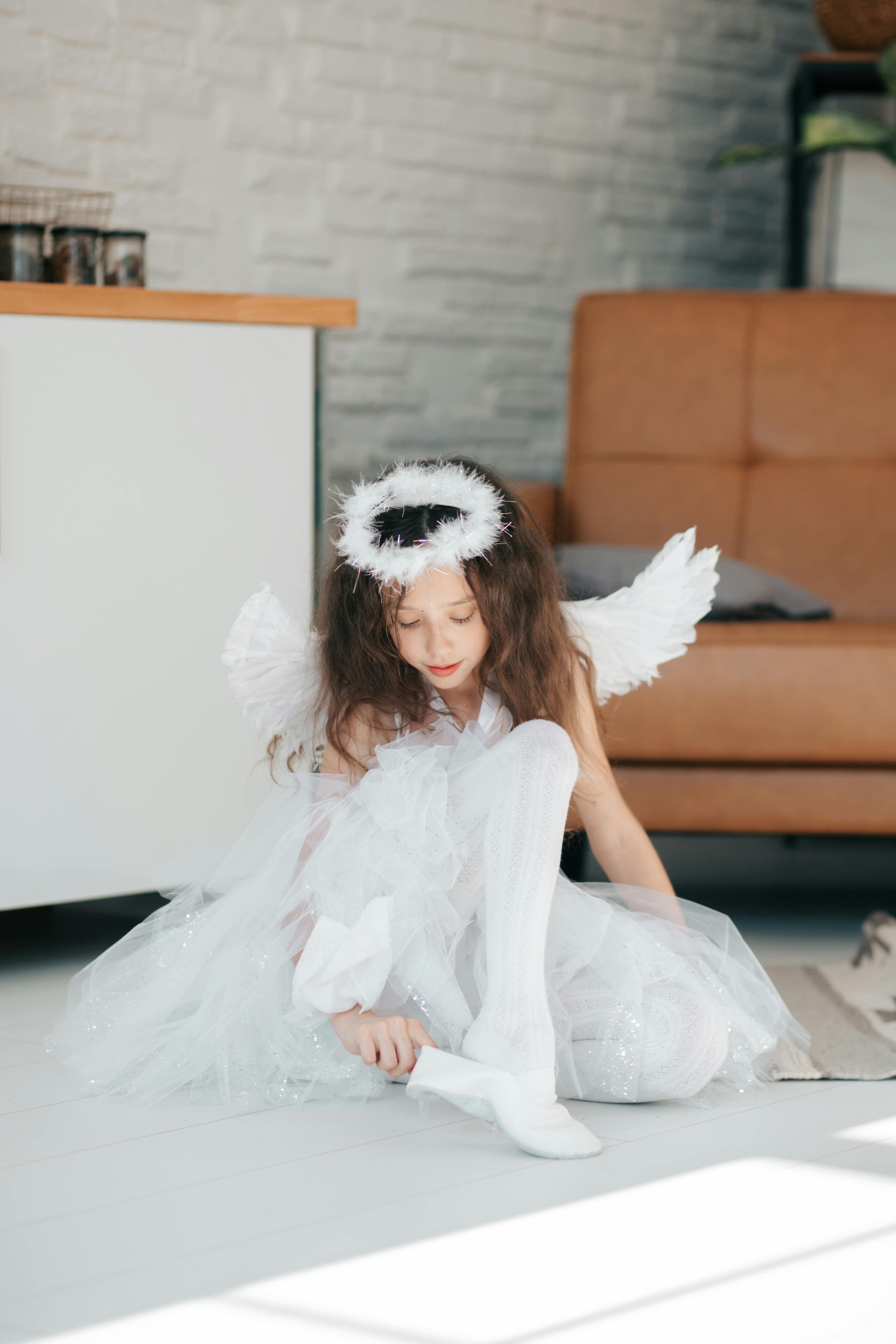 Cute Girl in Angel Costume Wearing Her White Shoe · Free Stock Photo