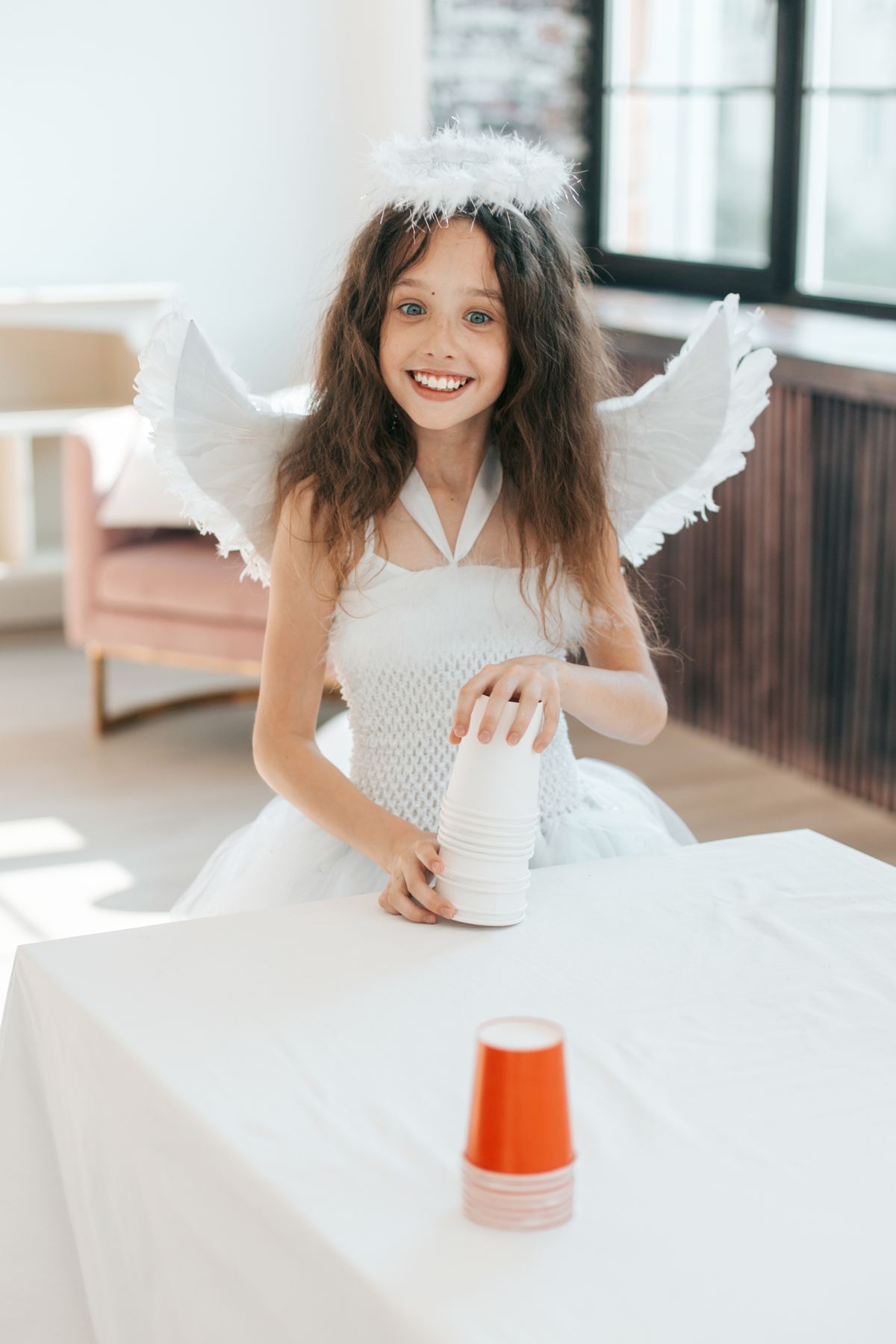 A young girl stacking paper cups on a table indoors