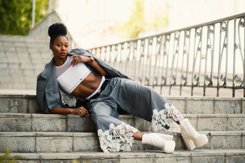 Woman Wearing White Sports Bra and Gray Pants Laying on Stairway