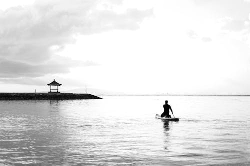 Grayscale Photo of Man Riding a Kayak on Sea