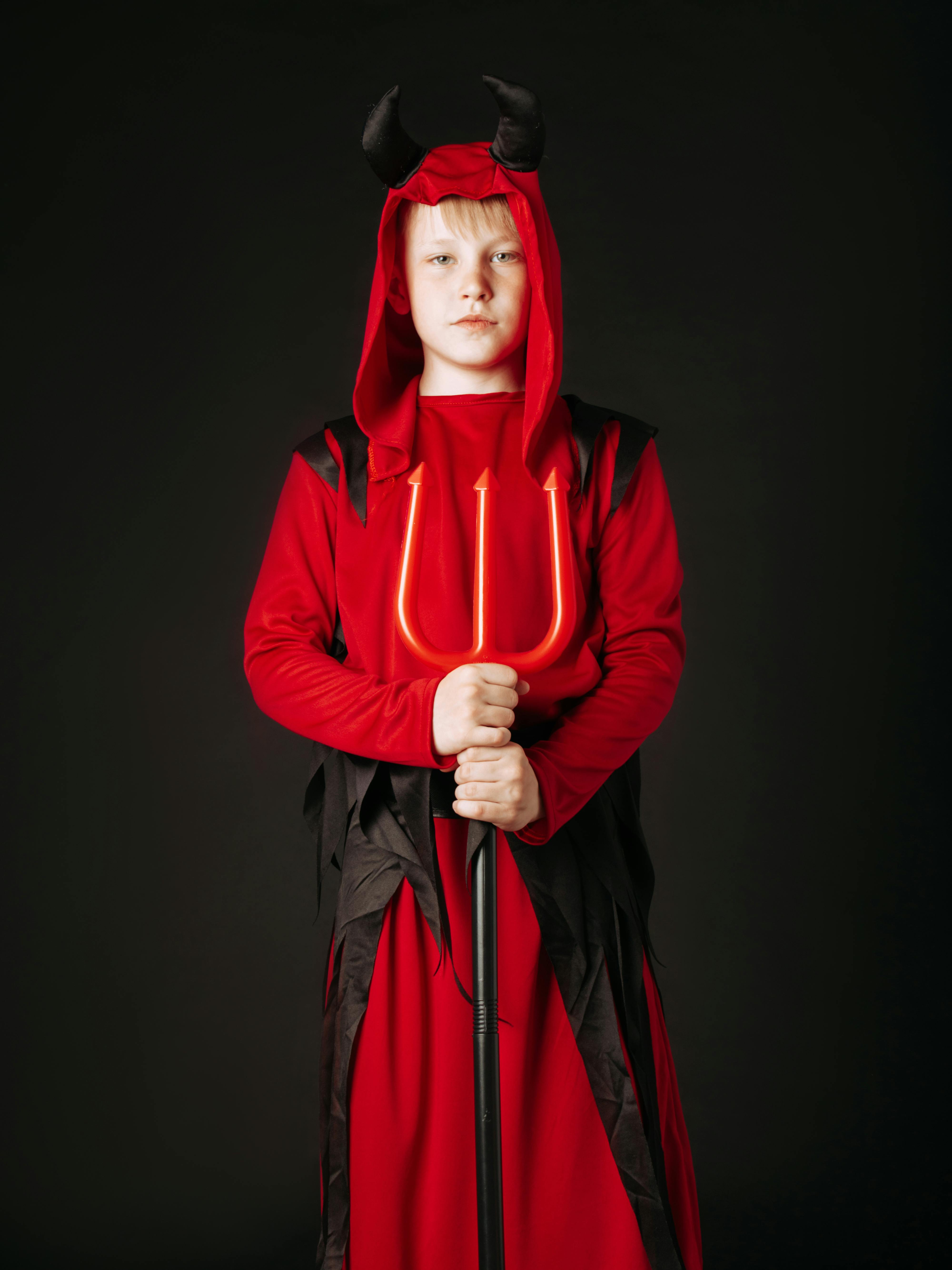 a boy in devil costume holding a trident