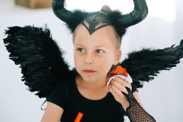 Girl In Devil Costume Eating A Cupcake