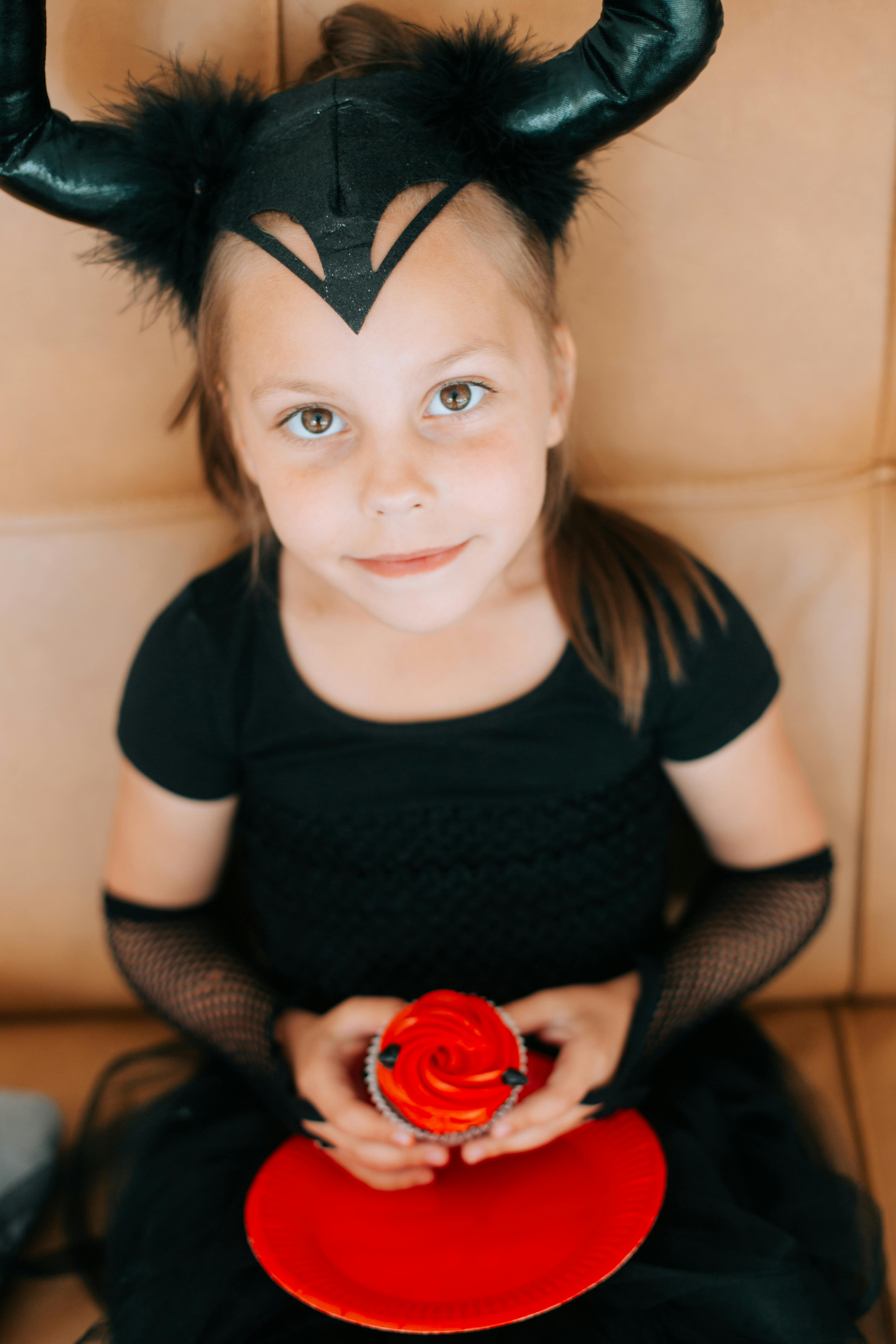 overhead shot of cute girl in devil costume holding a cupcake