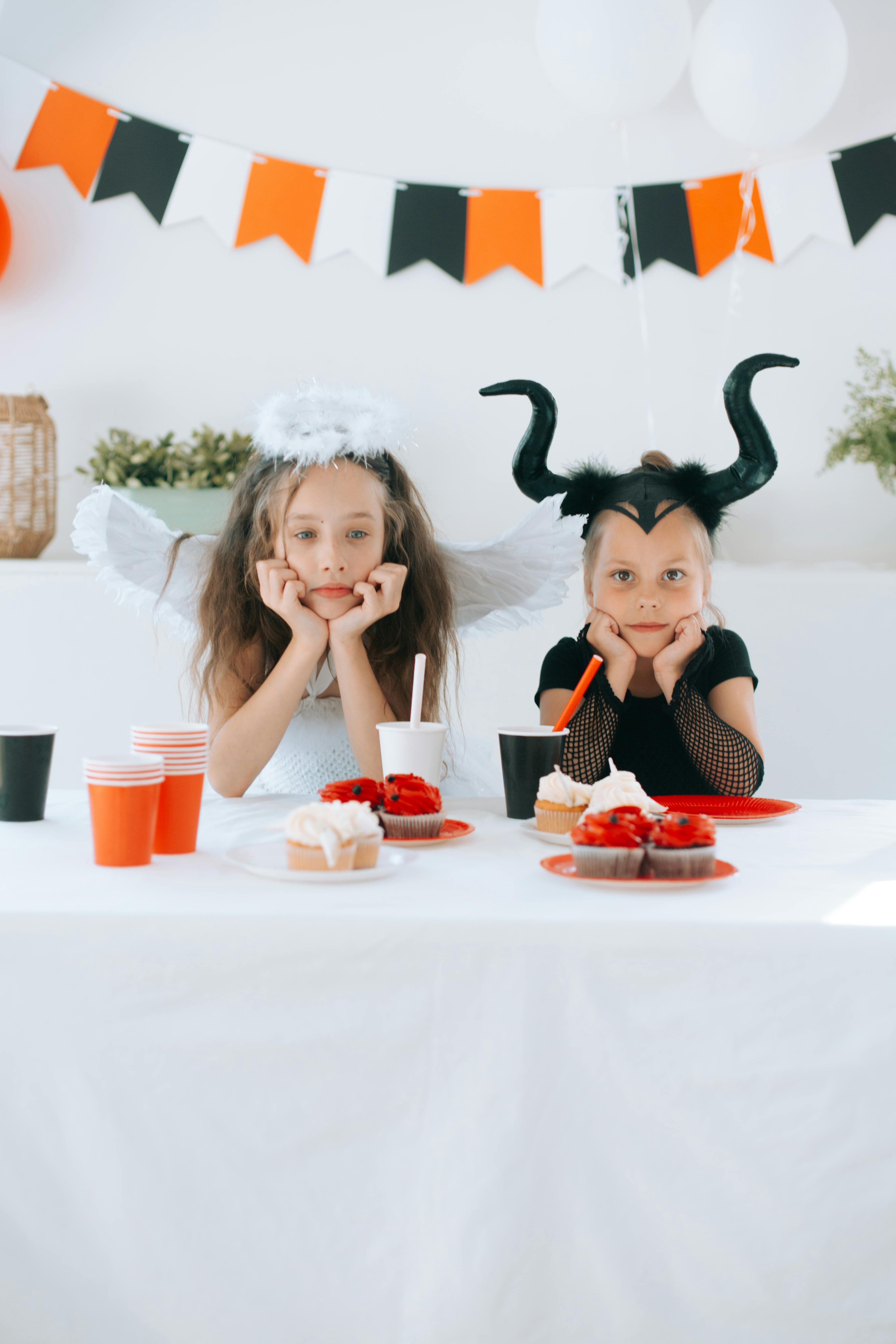 two girls in halloween costume leaning on a table