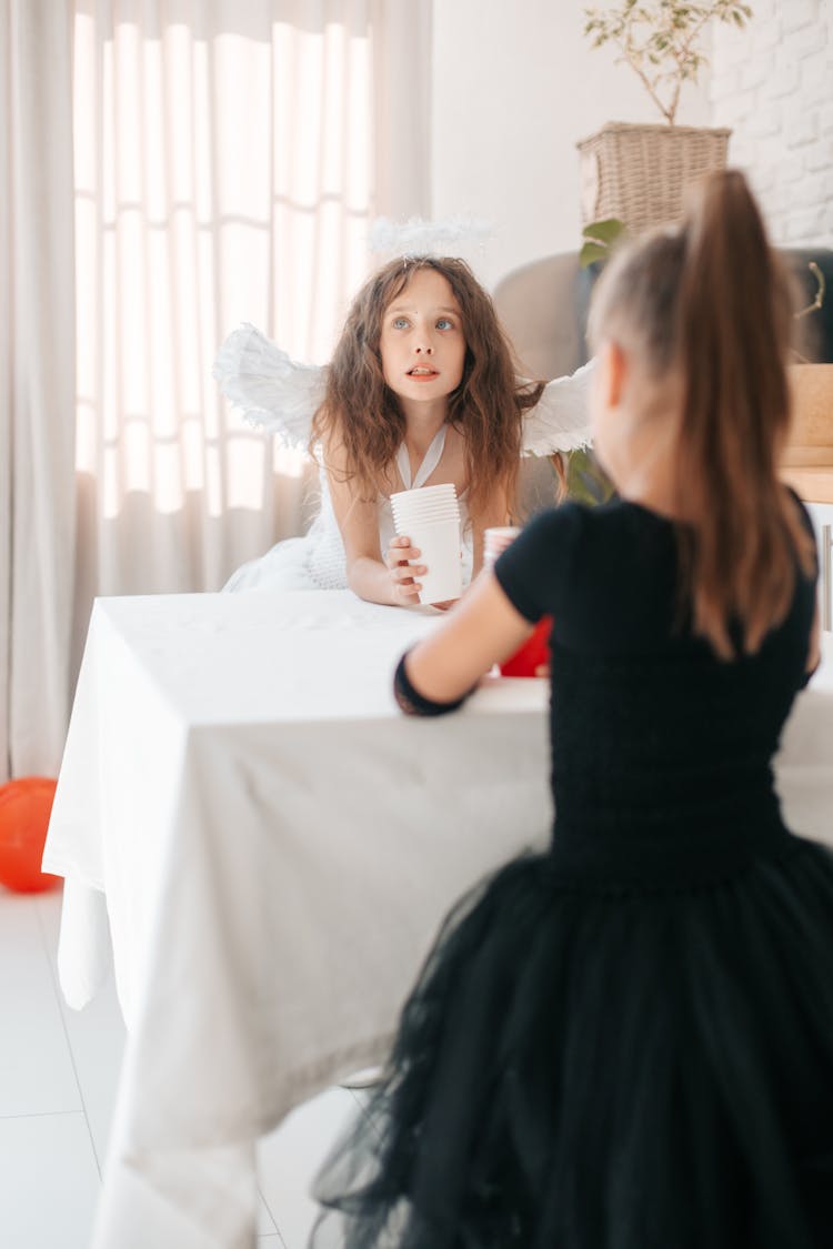 A Young Girls Wearing Costume While Sitting  Near The Table