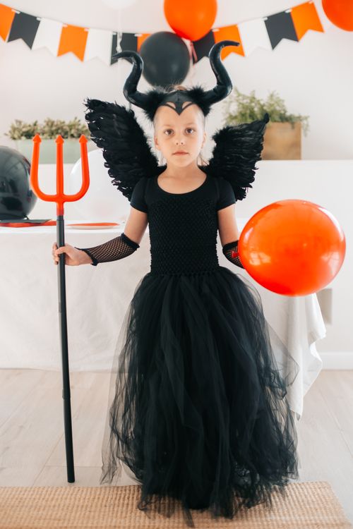Free Young girl dressed in devil costume holding balloons, perfect for Halloween themes. Stock Photo