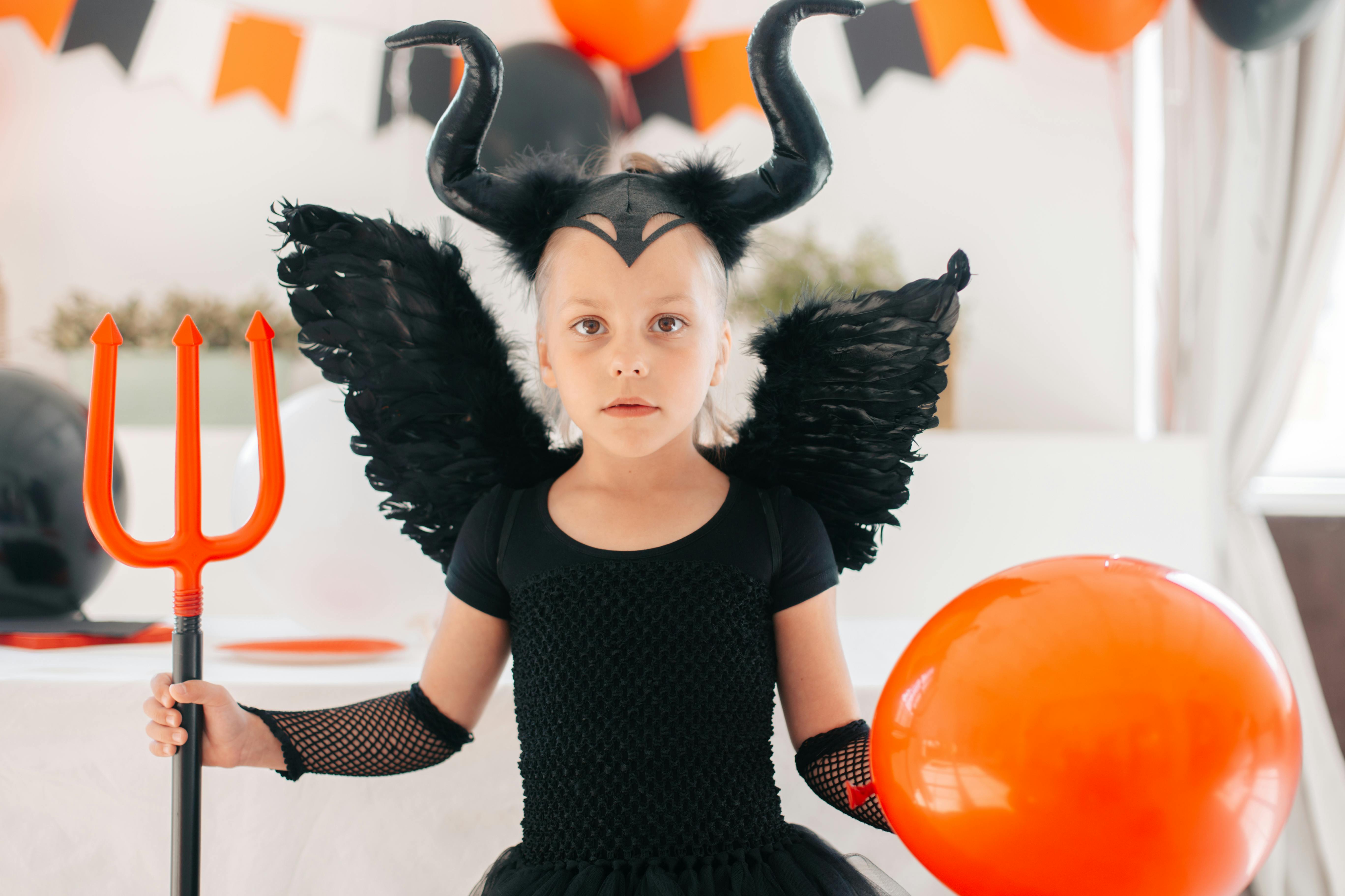 cute girl in devil costume holding a trident and balloon