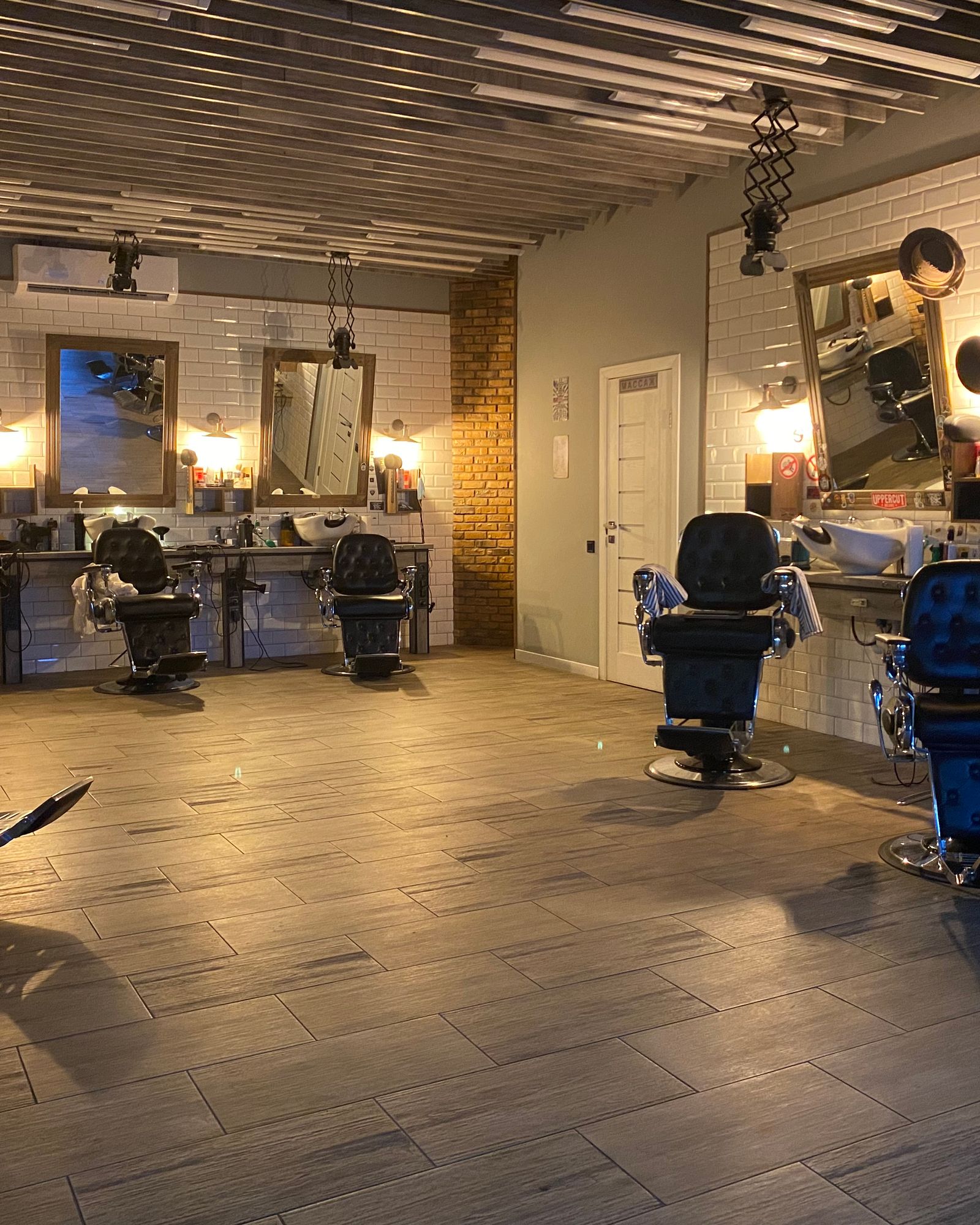 Interior do salão Gustavo Hentz Hair Beauty, cadeiras de barbeiro e espelhos com iluminação quente