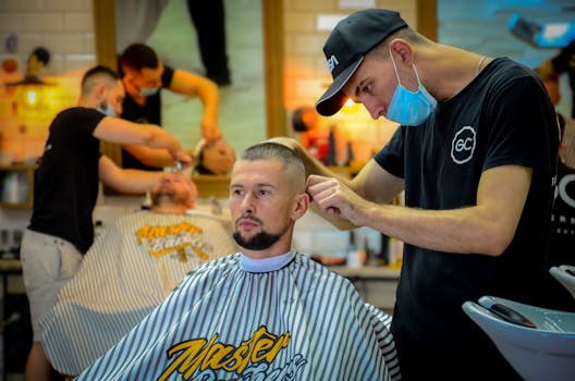 Male barber expertly cutting man's hair in a contemporary barber shop.