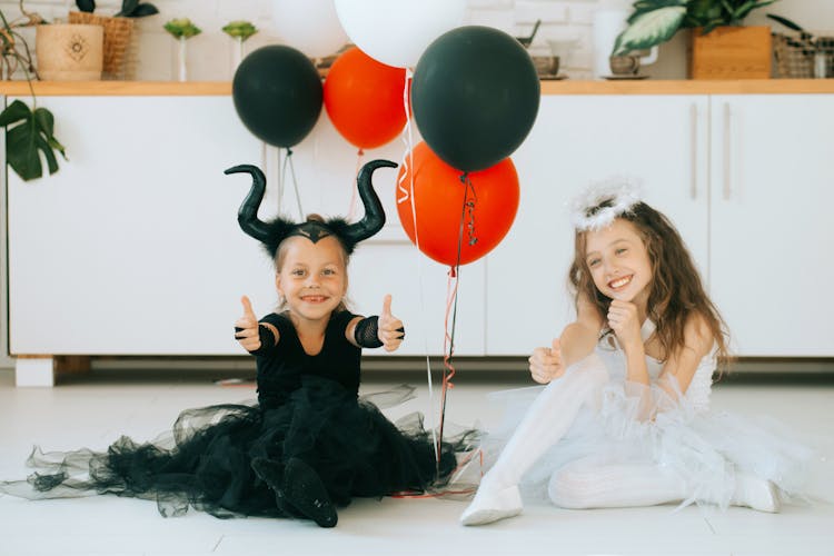 Two Cute Girls In Halloween Costume Sitting On The Floor