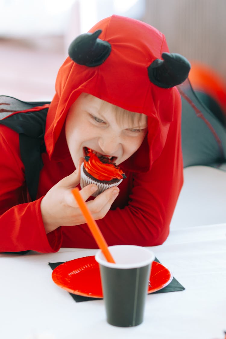 Boy In Devil Costume Eating A Cupcake