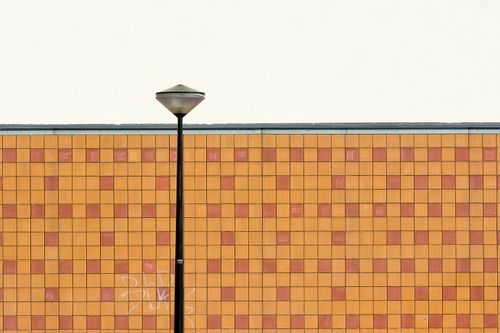 Free Streetlight in front of textured yellow and orange checkerboard wall with ample copyspace. Stock Photo