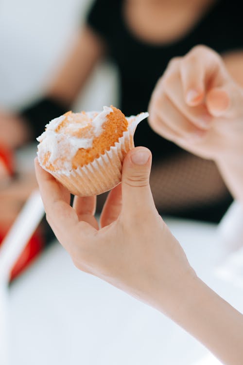 A Person Holding a Cupcake With Icing