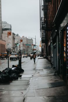 A rainy day in the city captures a pedestrian walking down a busy urban street.