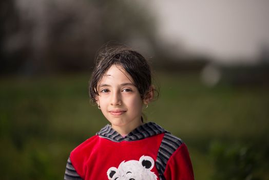 一位年轻女孩穿着红色毛衣，在户外微笑的迷人肖像