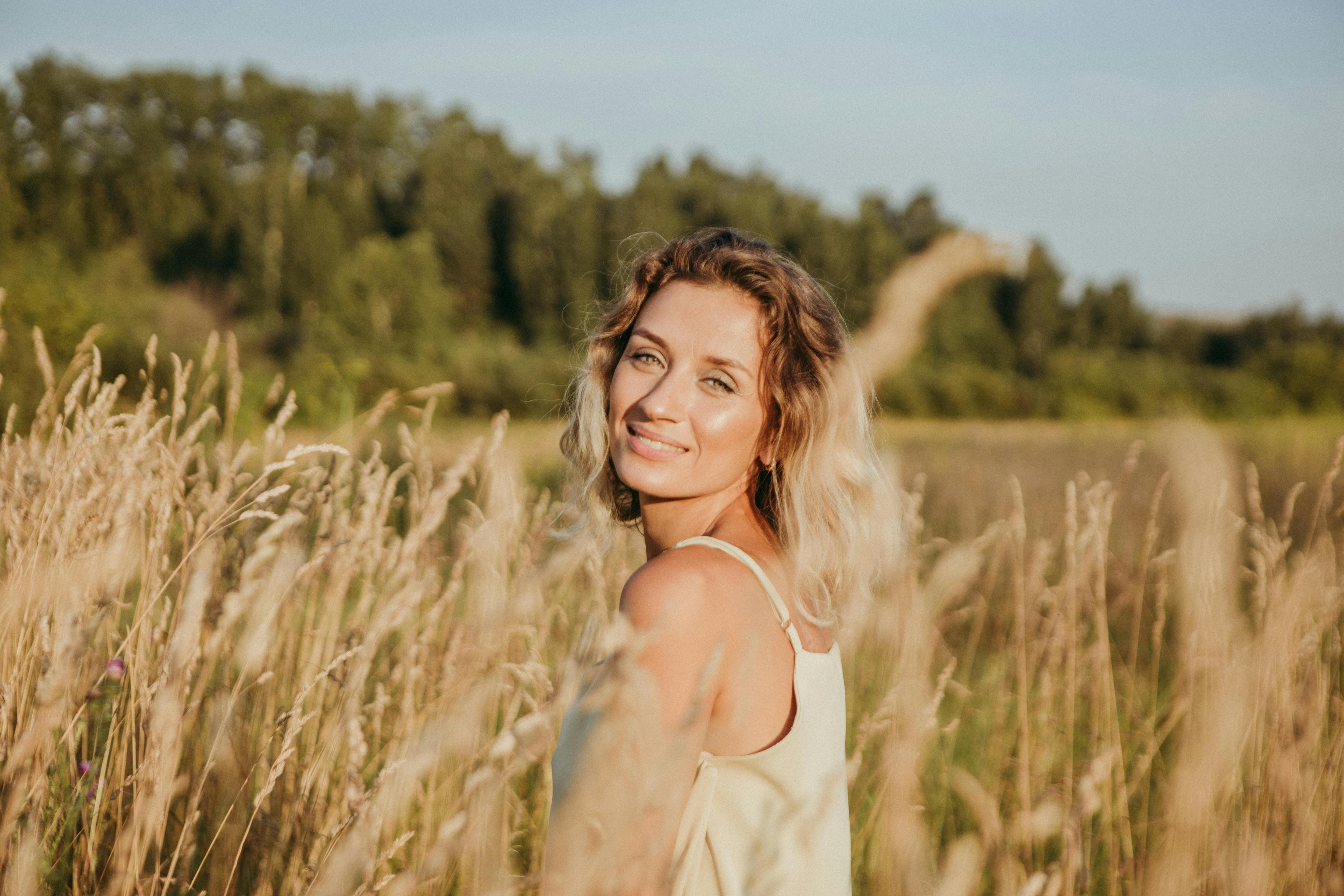Free Portrait of a woman enjoying the summer outdoors in a grassy countryside field. Stock Photo