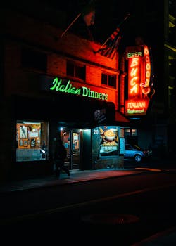 A vibrant neon-lit Italian restaurant in Pittsburgh at night, highlighting urban nightlife.