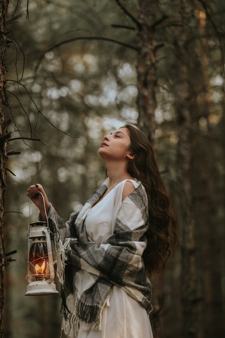 A Woman With A Scarf Holding A Fire Lamp