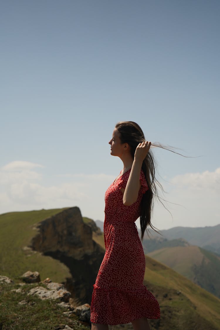 A Side View Of A Woman In Red Dress Standing The Cliff