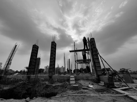 Black and white image capturing construction workers at a building site in Rasulpur, India.