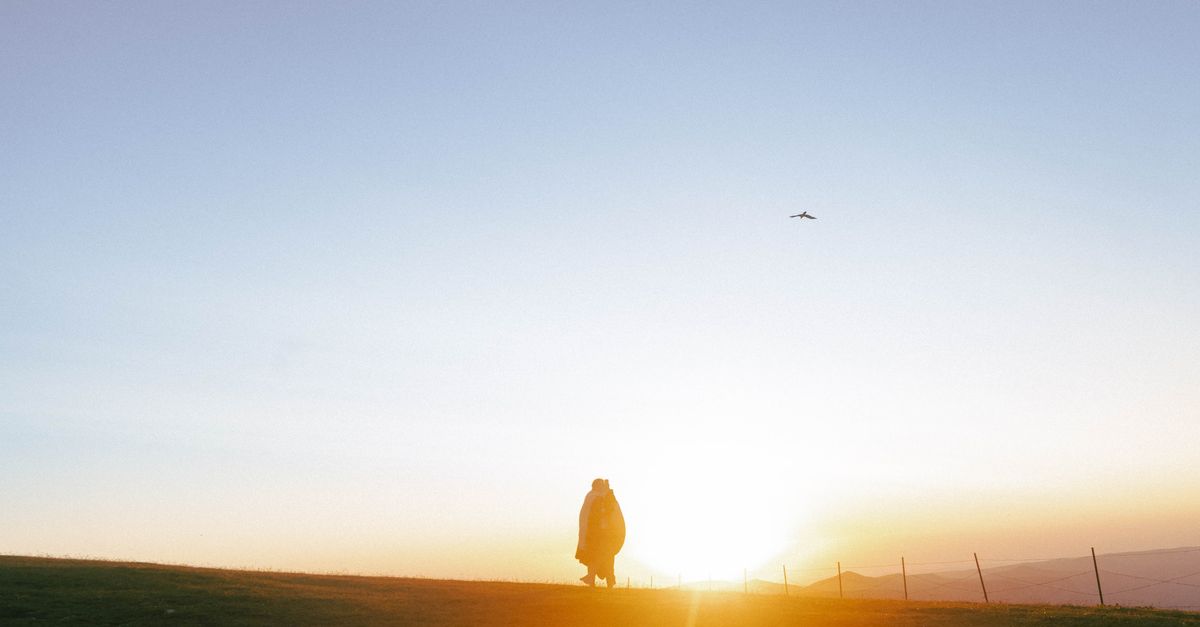 person walking outside in the morning sun, calm and mindful, no phone in hand