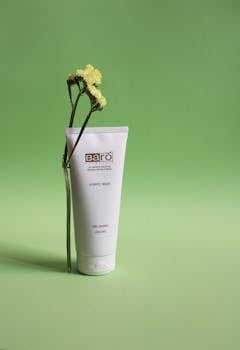 Minimalist skincare product shot with a floral touch on a green background.