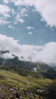 Breathtaking aerial view of the Dolomites in Veneto, featuring lush green hills and a winding road under a blue sky.