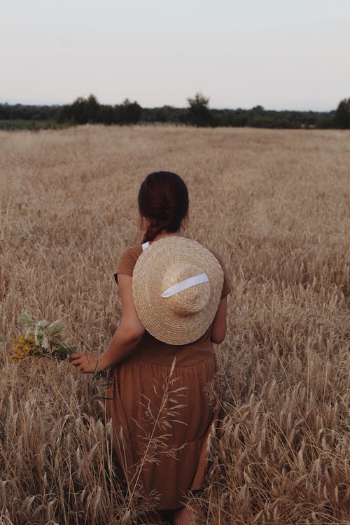 Woman in Brown Dress Walking in a Wheat Field