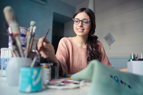 Free Woman in Brown Long-sleeved Shirt Wearing Eyeglasses Holding Paint Brush Stock Photo