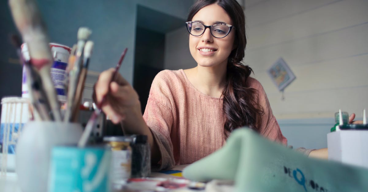 Woman in Brown Long-sleeved Shirt Wearing Eyeglasses Holding Paint Brush