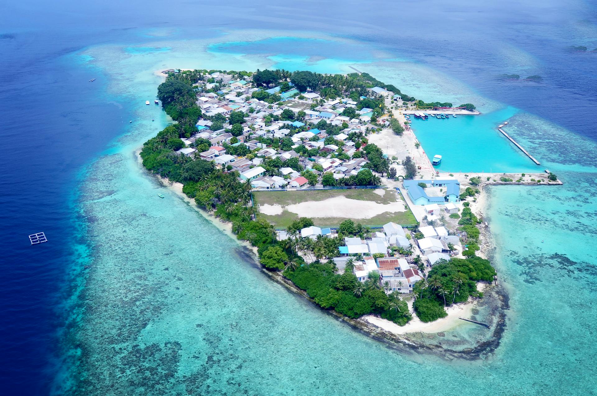 Stunning aerial view of a small island village surrounded by turquoise waters and coral reefs.