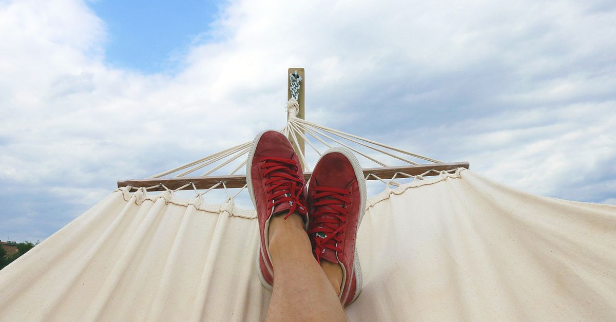 Rüyada Tatile Çıkmak - Rüya Tabiri ve Anlamı - Feet resting on a hammock with red sneakers, epitomizing summer relaxation and leisure outdoors.