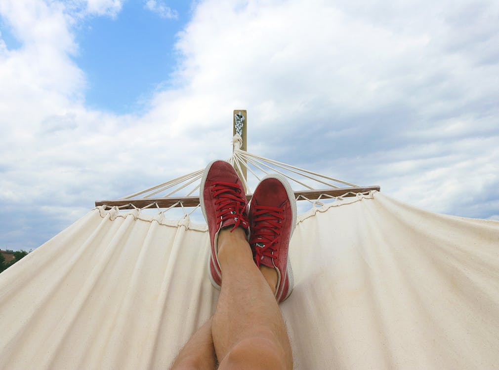 Person laying down on a hammock with their shoes on.