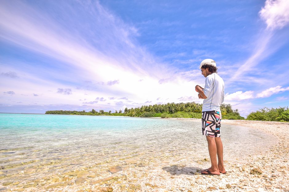 A man stands by the turquoise waters of a tropical beach in the Maldives, enjoying the serene ocean view.