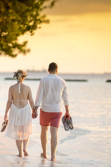 A couple holding hands walking on a tropical beach at sunset, creating a romantic scene with a golden sky. - The Ultimate Barbados Honeymoon Guide (2026): Romantic Getaways