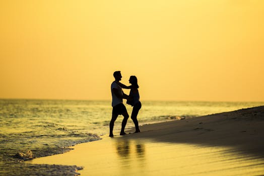 Silhouette of a couple embracing on a beach at sunset, capturing a romantic and serene moment.