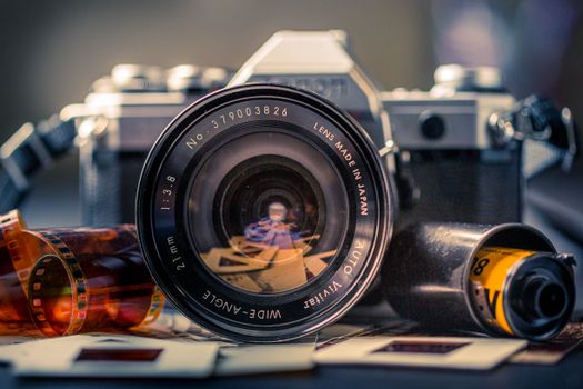 Close-up of a vintage film camera with film negatives and slide frames, capturing nostalgia.
