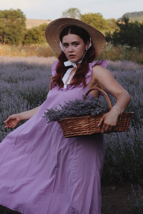Woman in Purple Dress and Sun Hat Holding a Wicker Basket with Lavender
