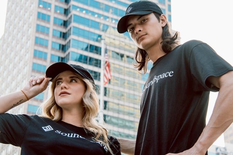 Photo Of Two People Wearing Black Shirts And Baseball Caps 