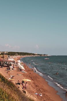 Lively Mediterranean beach scene with people enjoying the summer sun and sea.