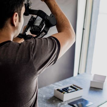 A man uses a stabilizer for camera filming indoors, capturing steady shots.